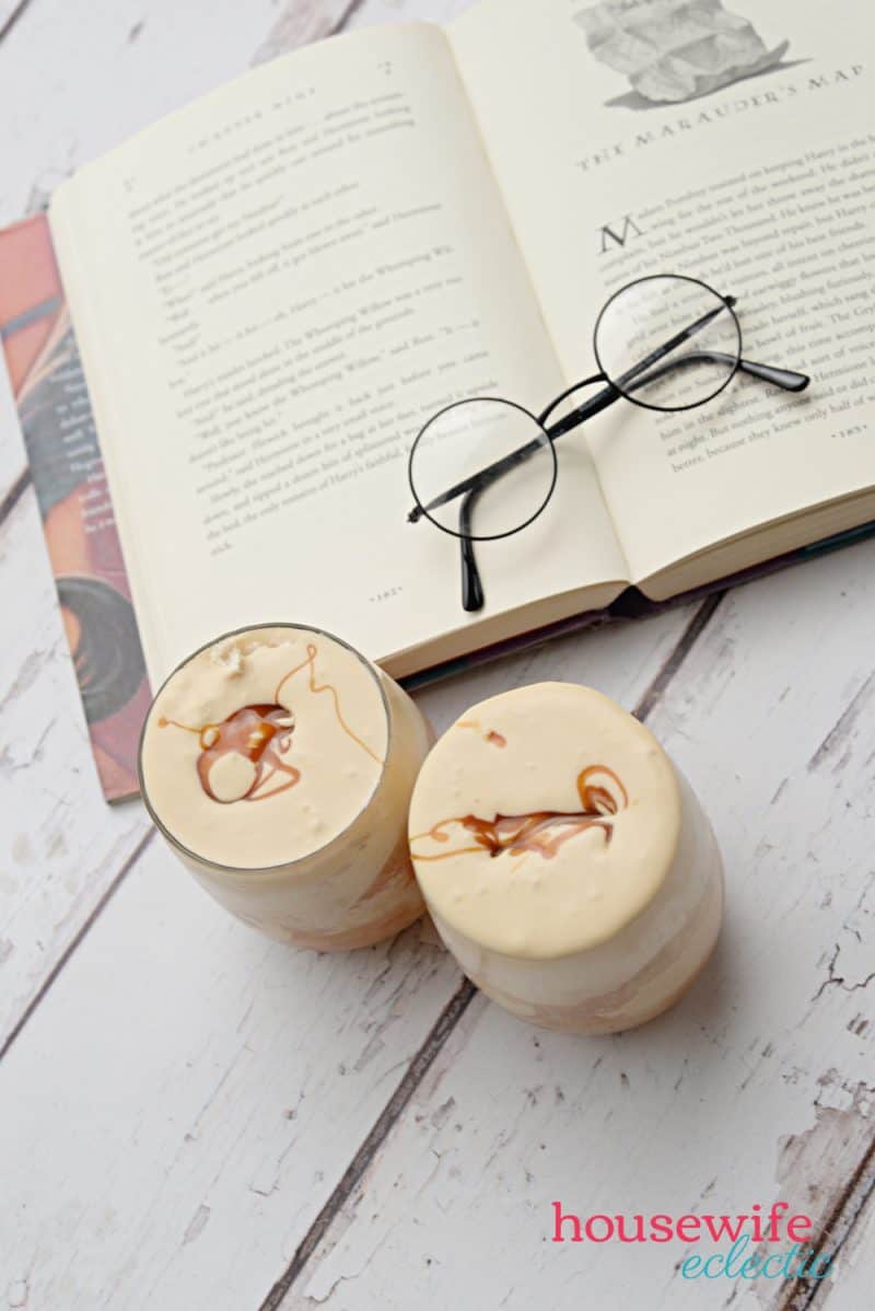 Two glasses of homemade butterbeer next to a Harry Potter book. 